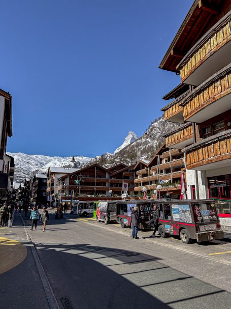 Zermatt mit Blick aufs Matterhorn Belebte Straße in alpinem Dorf mit schneebedeckten Bergen