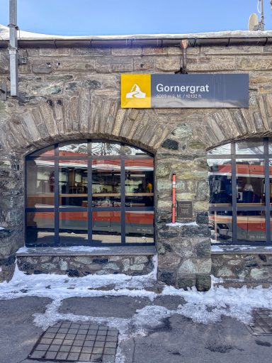 Bahnhofseingang Gornergrat mit Zug im Hintergrund