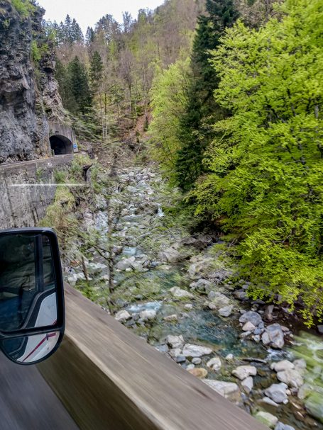 Vorbei an Bächen Flusslauf neben Straßenkurve mit Tunnel in den Schweizer Alpen