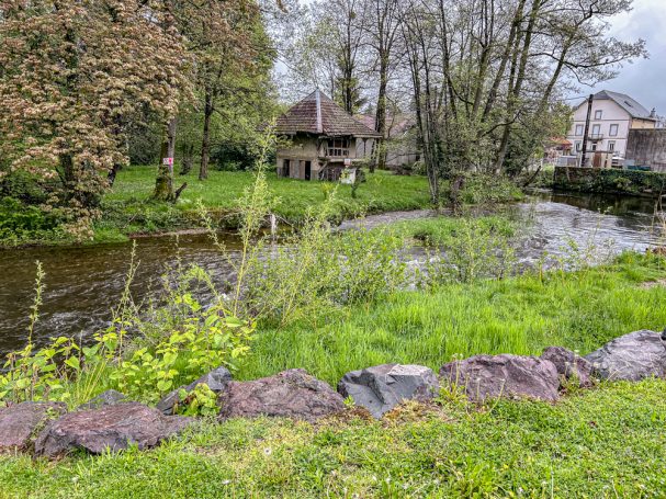 Der Bach am Stellplatz Fluss mit Bäumen und Haus im Fougerolles-Saint-Valbert