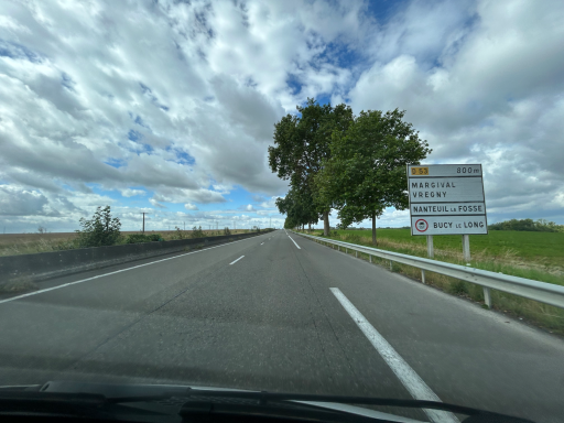 Landstraße mit Hinweisschild in ländlicher Gegend Frankreichs