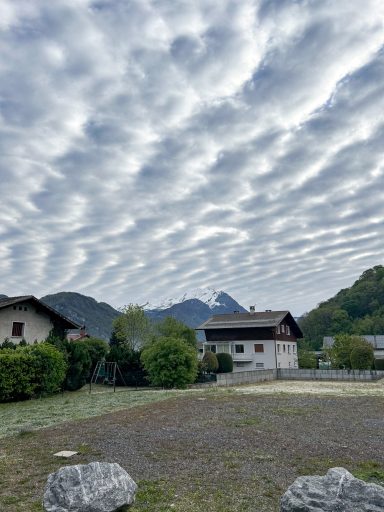 Wohnhäuser in alpiner Umgebung unter wolkenverhangenem Himmel
