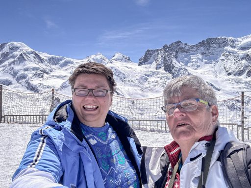 Zwei Personen vor schneebedeckter Alpenlandschaft