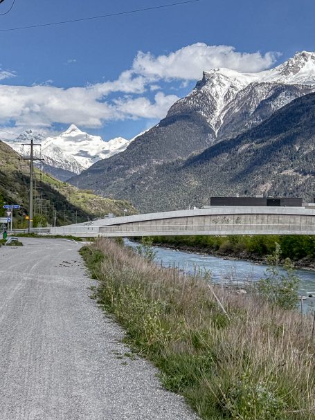 Brücke über die Rhone oder Rotten Schneebedeckte Berge mit Fluss und moderner Brücke