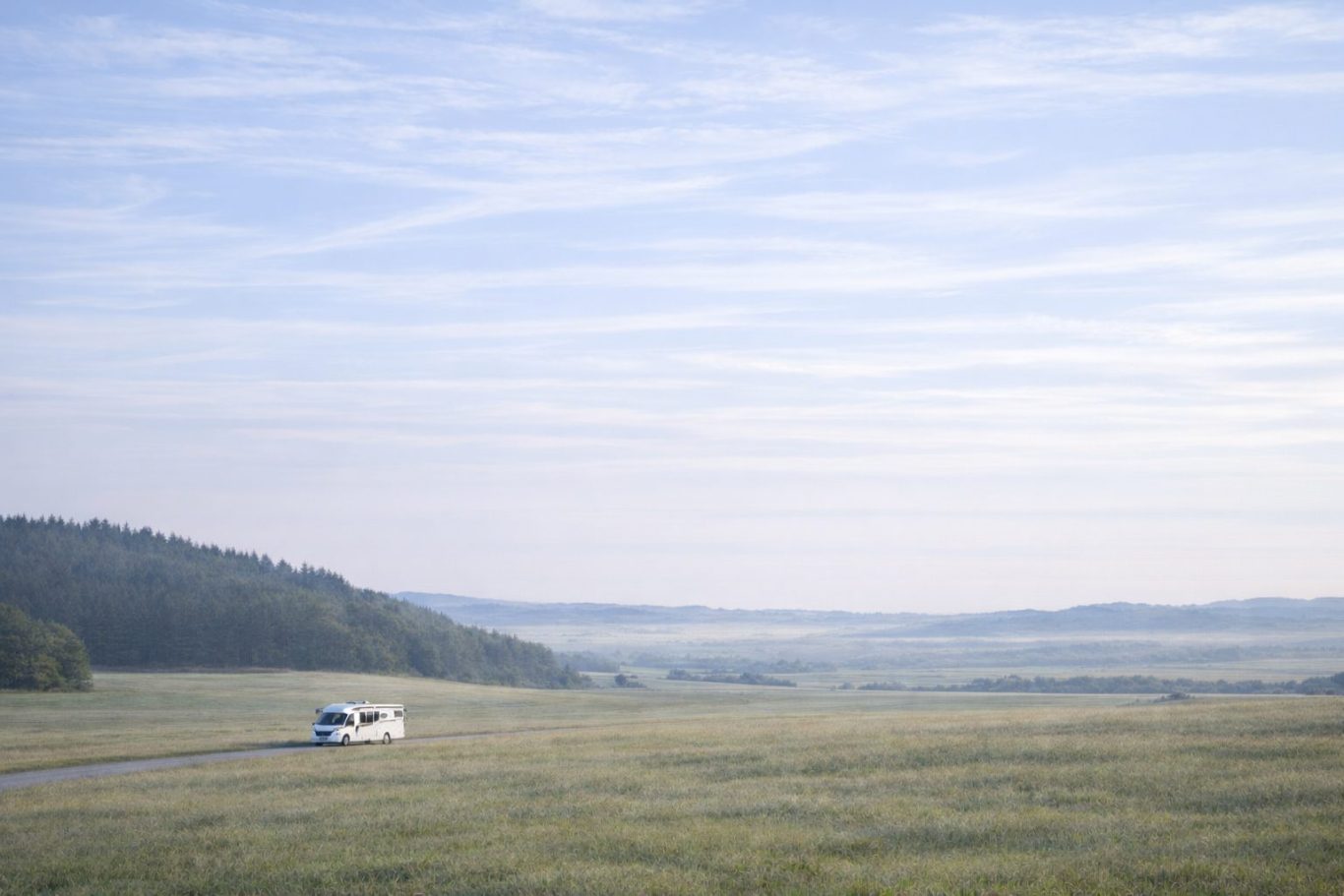 Wohnmobil unterwegs auf ruhiger Straße durch weite Landschaft in Europa