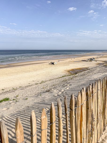 Ein schöner Strand mit sanften Wellen und einem Holzzaun im Vordergrund.