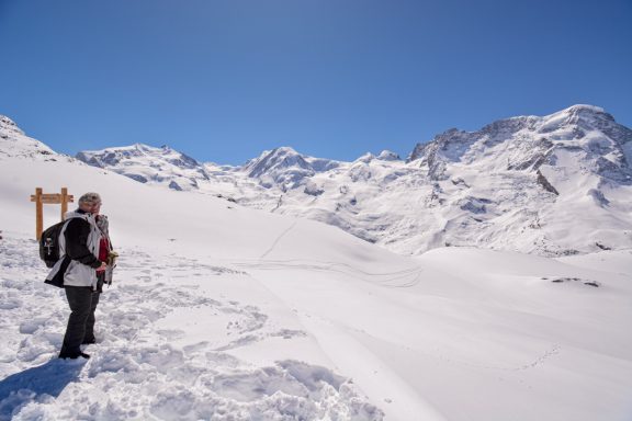 Weite Schneelandschaft mit Bergen unter blauem Himmel