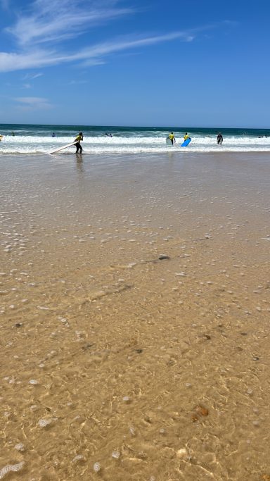 Menschen mit Surfboards im flachen Wasser am Atlantikstrand
