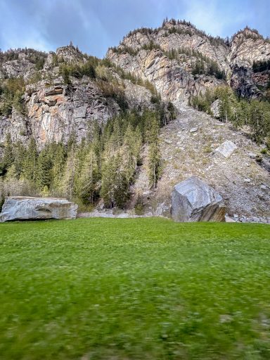 Felsige Berghänge mit Wiesen und Bäumen im Tal