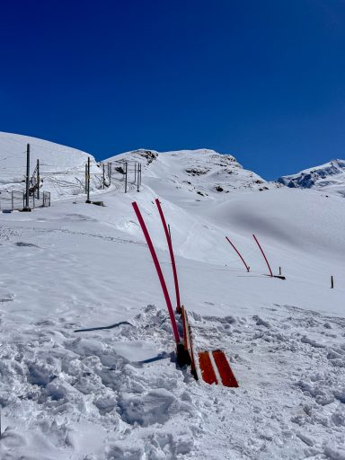 Skipiste mit roten Markierungsstangen in hochalpiner Landschaft