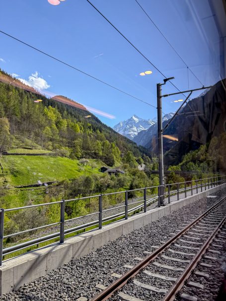 Der letzte Blick vorm Tunnel Blick aus dem Zugfenster auf grüne Hügel und schneebedeckte Berge