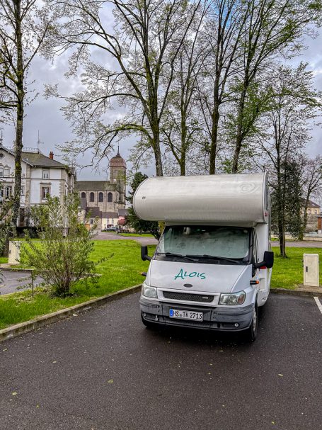 Stellplatz in Fougerolles-Saint-Valbert Wohnmobil auf Parkplatz vor historischer Architektur in französischer Umgebung